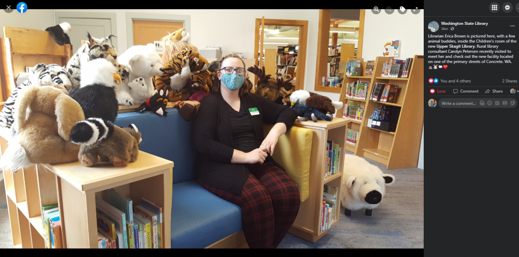 Screenshot of a Facebook post by the Washington State Library, with new library Director Erica Brown sitting on an oversize chair with built-in bookshelves and a dozen stuffed animals surrounding her.
