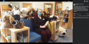 Screenshot of a Facebook post by the Washington State Library, with new library Director Erica Brown sitting on an oversize chair with built-in bookshelves and a dozen stuffed animals surrounding her.